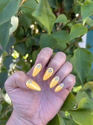 Acrylic almond shaped nails in yellow with chrome finish. Topped with jewels.