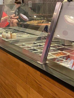 Employee sitting on the counter directly next to where pizzas are prepared for pick up!