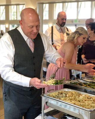 Groom dishing his plate as he goes through Buffet at wedding in Port Gamble