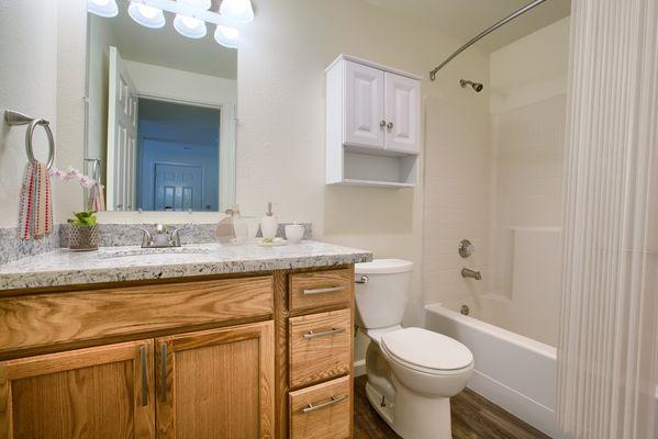 Bathroom with granite countertops, soft-close cabinetry and curved shower curtain bar.