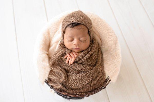 Tiny little potato sack portrait newborn baby in brown knit wrap and knit bonnet inside egg basket Gainesville FL