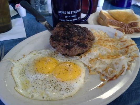 Two eggs sunny side up with chopped steak and hash browns.