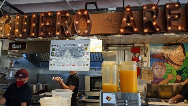 Arepas on the grill in the back. Passion fruit juice on the front counter.