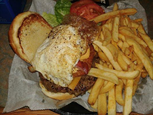 The Gladstoner, consisting of a beef patty, American cheese, cheese sauce, topped with a fried egg, bacon, onion ring, tomato, lettuce.