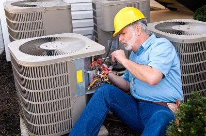 Technician configuring wiring on an AC unit.