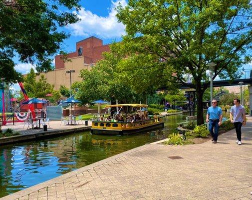 A Bricktown Water Taxi cruises past Brickopolis mini golf on a beautiful day in July, 2021