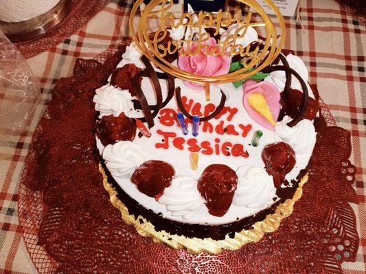 Chocolate sponge cake, chocolate shavings on the side, with cherries on top.