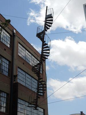 Spiral fire escape sculpture titled Architectural DNA between buildings