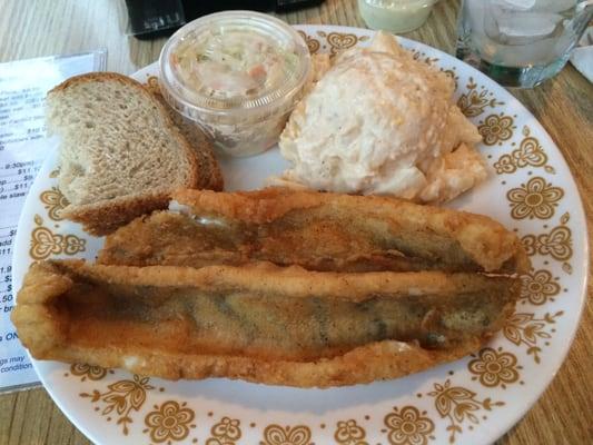 Walleye dinner plate with potatoe salad, coleslaw and rye bread.