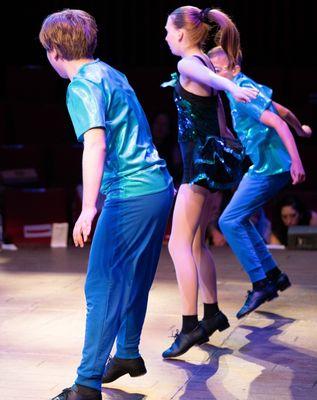 Three advanced teen Tap dancers Tap dancing on stage in costume.