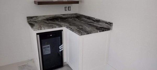 Built in mini fridge with marble countertops painted walls and cabinets