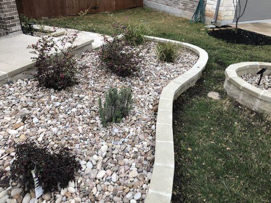 flower bed with new plants installed and fisnish up with a decorative riverrock