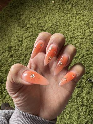 Orange burst nails with gold chrome stars and stones