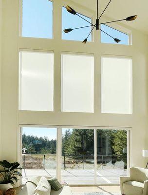 Angled windows and roller shades in modern living room.