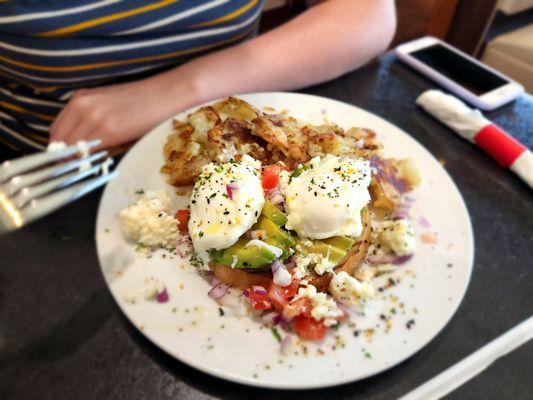 Avocado toast with eggs and home fries and a lot of feta cheese.