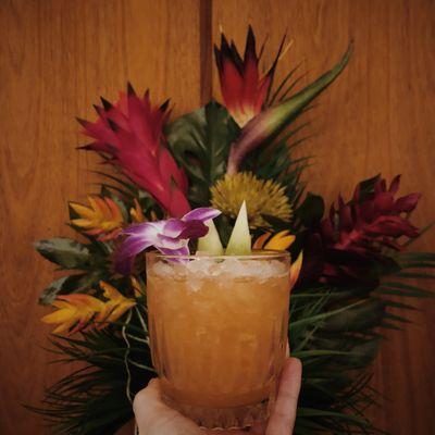 One of our newer cocktails called Dawn, featuring mezcal, aperol, pineapple, lemon, & cane sugar, garnished with an edible orchid.