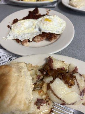 Corned beef hash with over medium eggs, homefries, and a biscuit