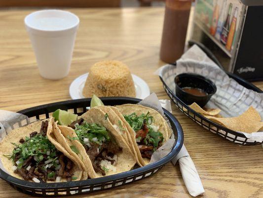 Carne asada and al pastor tacos with a side of rice. Complimentary chips and salsa