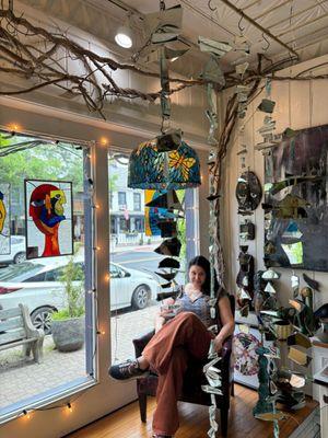 Owner, Carrie, sitting in the display window.  Stained glass by Laura Lutton.