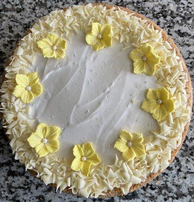 Key lime cheesecake with white chocolate shavings and special celebration edible flower decoration.