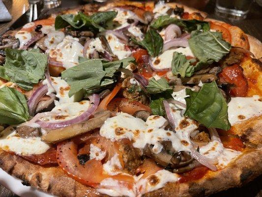 A custom pizza that was filled with fresh vegetables and tasty meats