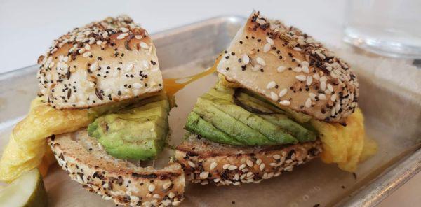 Breakfast sandwich with added avacado on everything bagel