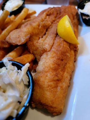 A photo of my fish and chips meal, including coleslaw, a lemon wedge, tartar sauce, and some of the best French fries I've ever had