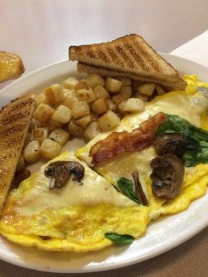 I made my own omlette!  Eggs, mushroom, spinach, & bacon with home fries and white toast.