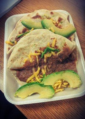 Bean and cheese tacos with flour tortillas and avocado.