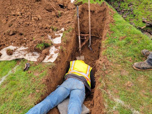 NOT laying down on the job! Getting up close to the connection point into the septic tank