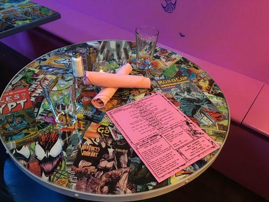 Each table is covered with an assortment of comic book pages.