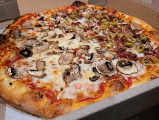 Fluffy, chewy pizza with double mushrooms, bacon and green olive on half.