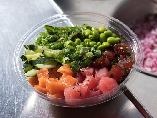 Koibito Signature Bowl - Salmon, Hawaiian tuna, & ahi tuna, sriracha aioli, cucumber, edamame, cilantro, seaweed salad, & sesame seeds.