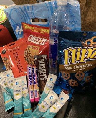 Red eye flight snacks: Cheez-It, Flipz Chocolate Pretzels, Mentos, Chili Pistachio, Smart Water, & free "Liquid IV" powder mix