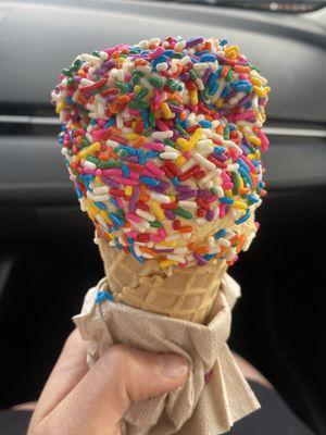 Mango ice cream w/ rainbow sprinkles in a waffle cone