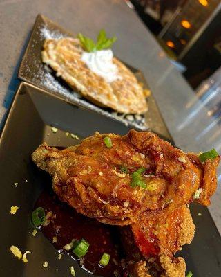 Hot honey country fried chicken paired with waffle topped with lemon buttercream icing and fresh whipped topping