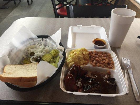 Beef brisket and sausage plate with potato salad and baked beans, with a side of jalapenos, onions, pickles and bread.