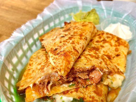 Birria quesadilla with a side of guacamole and sour cream. Cheesy and full of birria flavor. Highly recommend ordering!