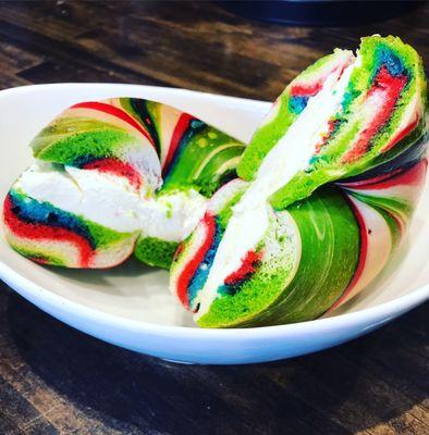 Rainbow bagel with cream cheese.  Our bagels are freshly baked on premise every day.