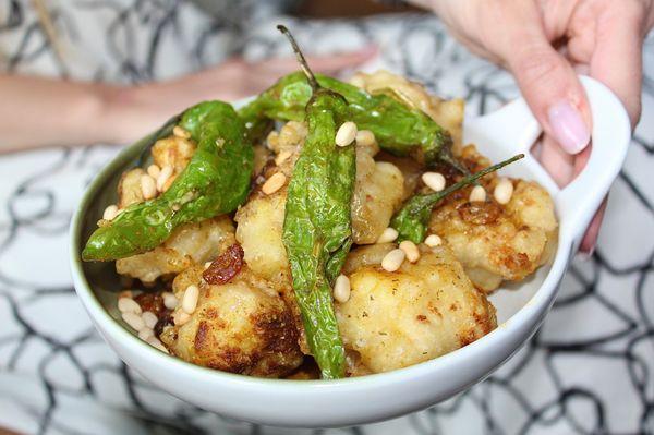 The Crispy Curried Cauliflower is made with blistered shishito peppers, golden raisins, pine nuts, and herbs de provence gastrique.