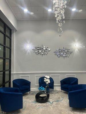 Office lobby, blue chairs with elegant crystal chandelier.