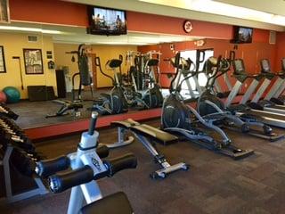 Fitness center with 3 treadmills, 2 elliptical machines, universal gym, recumbent bike, free weights & bench, punching bag, & tanning bed