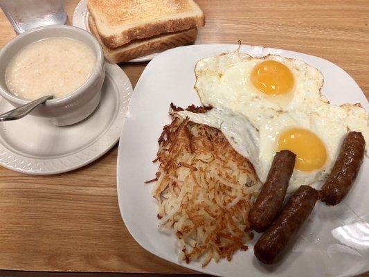 Breakfast plate with sausage links, eggs sunny side up, and hash browns with white toast. We added a side of grits.