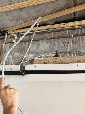 Ceiling flexible conduit run outside of wall surface