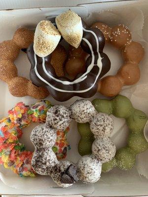 Chocolate w/ Smores, Cookies & Cream, Cinnamon Sugar, Milk Tea, Fruity Pebbles, Matcha mochi donuts