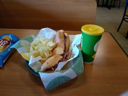 Delicious Meatball marinara sub with red onions, serves with salt & vinegar chips and a Sprite.