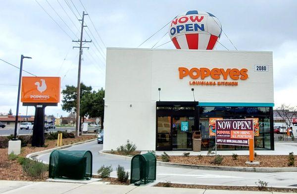 "Now open" balloon and sign. It says, "Now hiring for all positions".