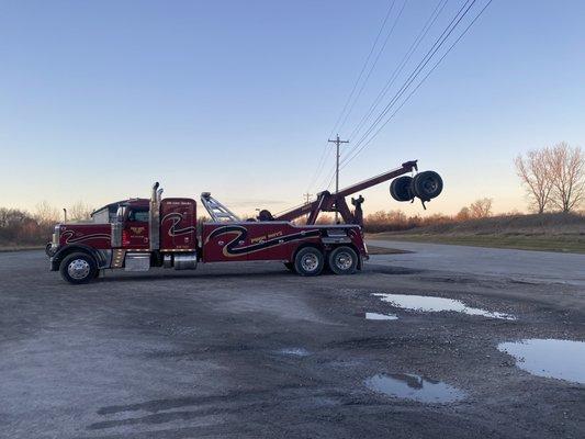 Heavy wrecker loading a torn out rear axle of semi trailer