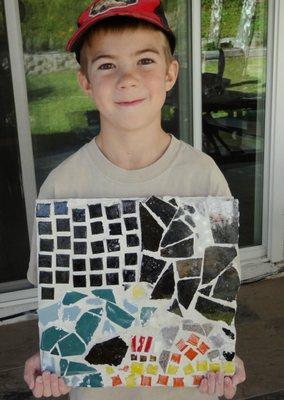 This young boy is very proud of his mosaic design.  Students can pick from a variety of shapes to create their unique design.