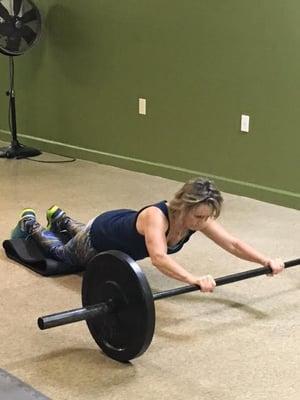 Trainer Linda Bock performing a 90lb barbell roll out.